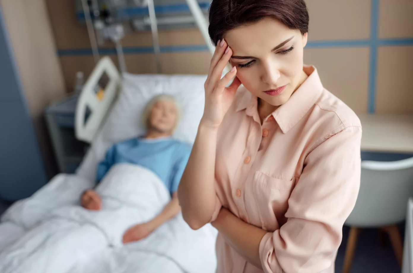 A caregiver looks distressed with a patient in the background